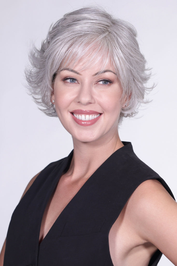 Model styling a short length pixie cut wig with a flip at the end and bangs.