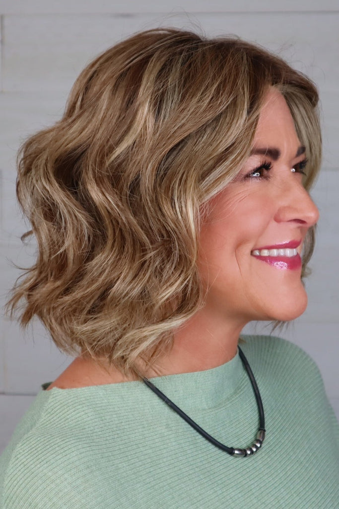 Side view of model wearing a short wavy wigs.
