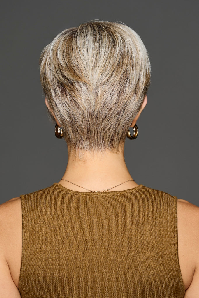 Back view of model styling a dark rooted light ash blonde wig blended with cool platinum blonde.
