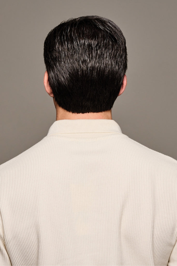 Back of male model styling a dark brown wig with 5% grey.