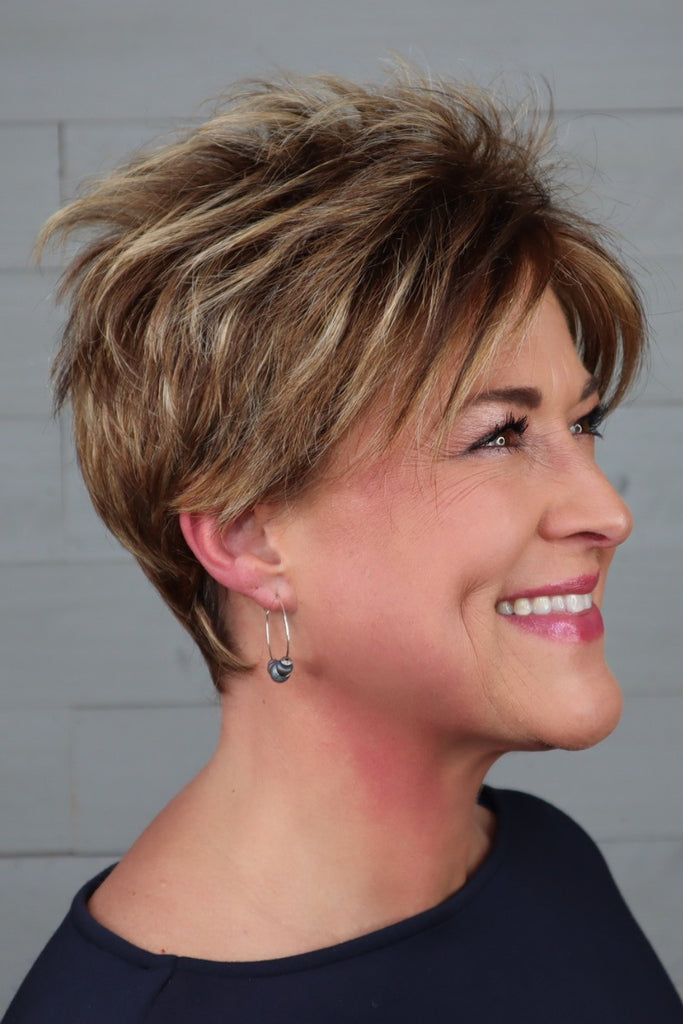 Side of woman wearing a short pixie wig.