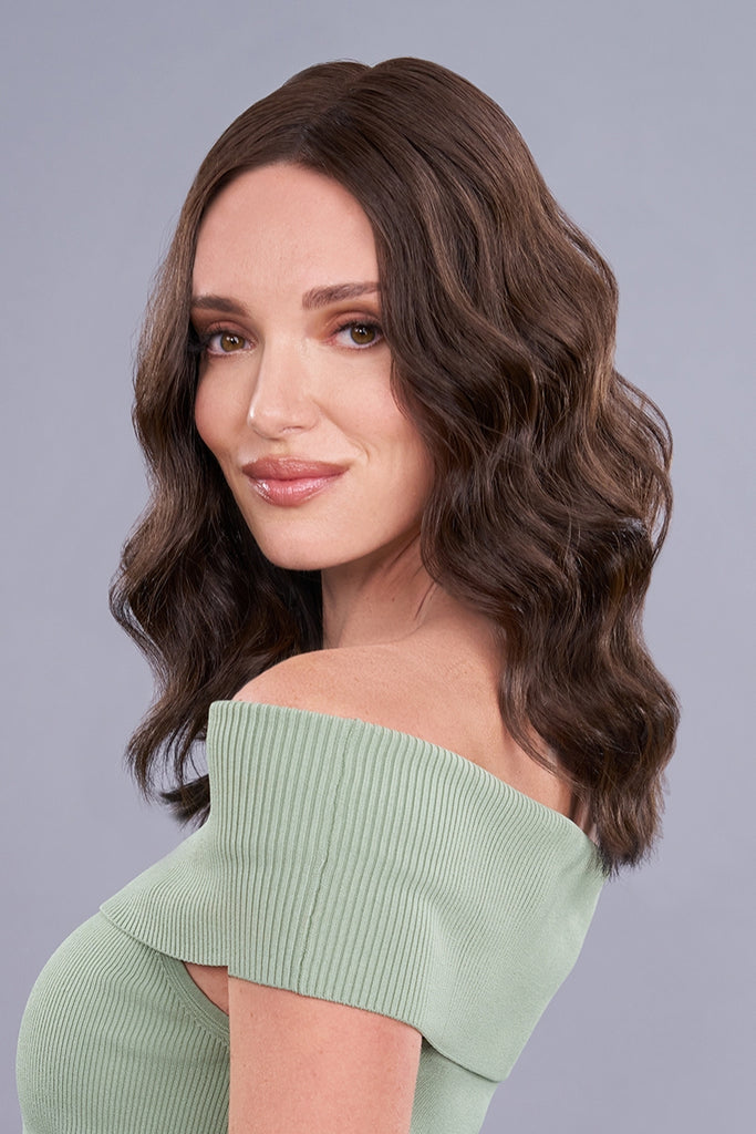Close up of model wearing a medium length wavy topper.
