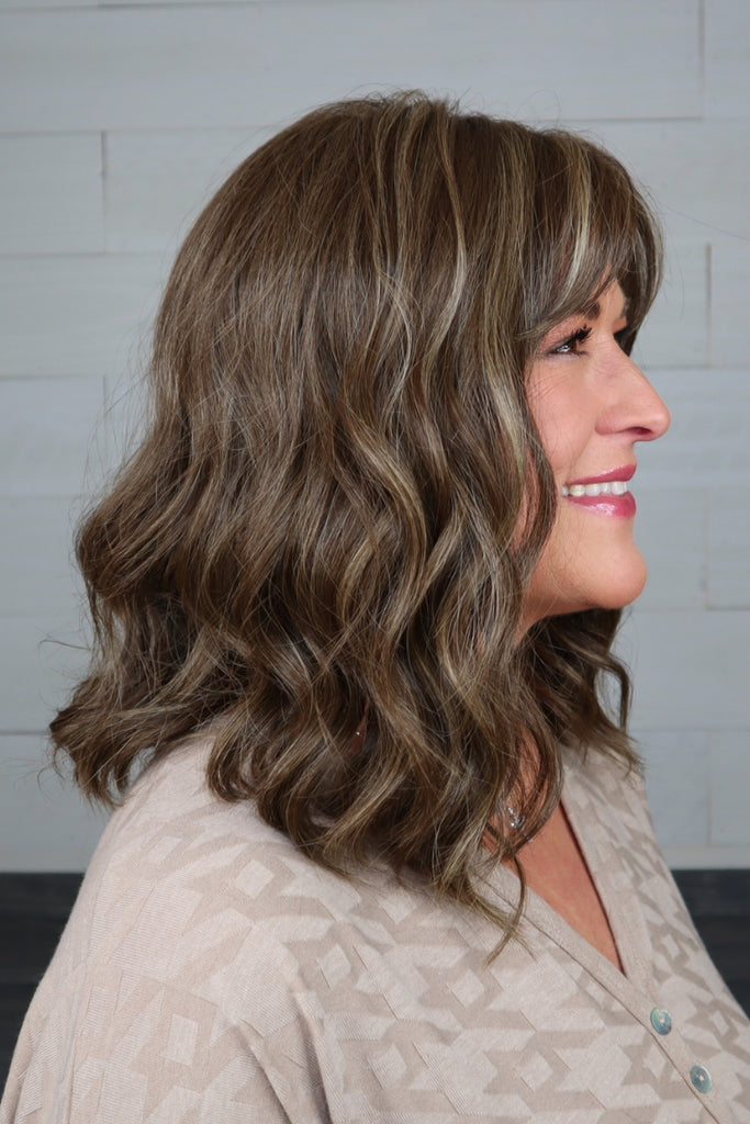 Model styling a shoulder length, wavy wig.