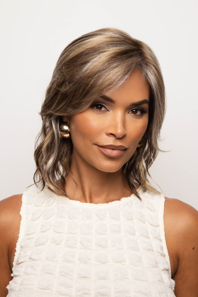 Model styling a wavy medium length wig in the color Sparkling Mocha.