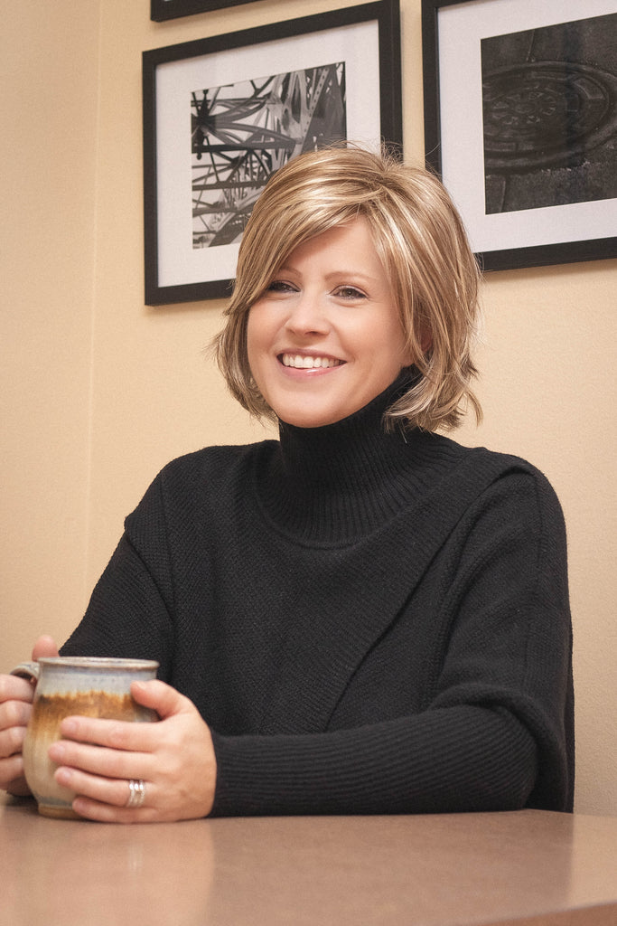 Woman wearing a blonde shag bob wig while drinking coffee.Model wearing Tony of Beverly wig Starly 2.