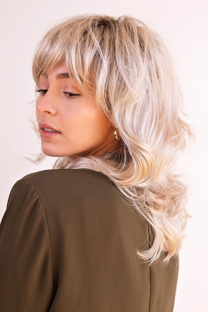 Close up of woman wearing a shagging wig wig with bangs.